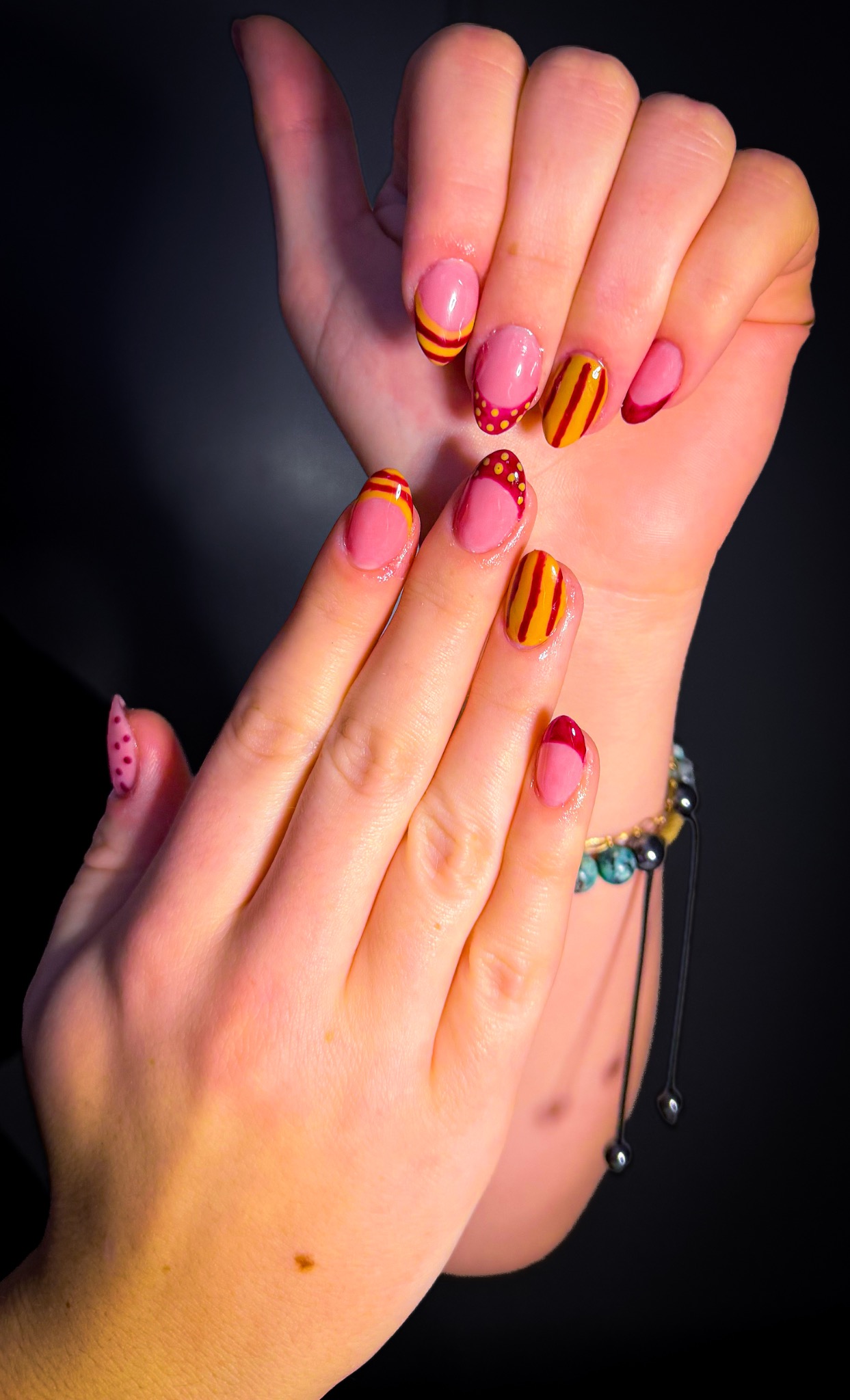 Pink, burgundy and golden-yellow nails with stripes and dots